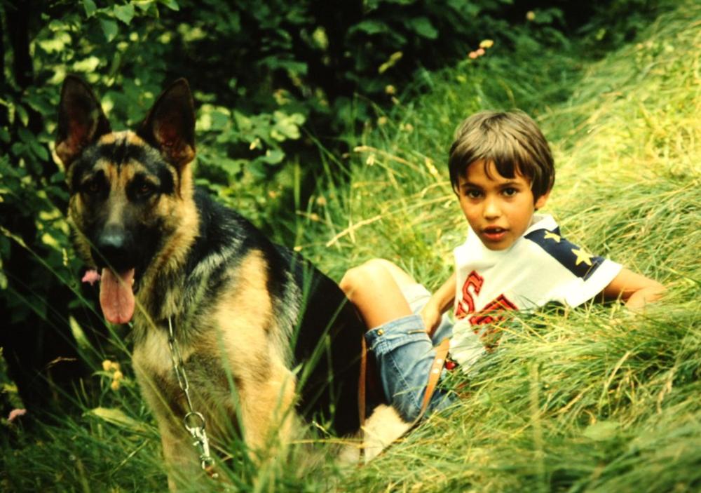 Davide Bergamaschi da bambino seduto nell'erba accanto al suo pastore tedesco